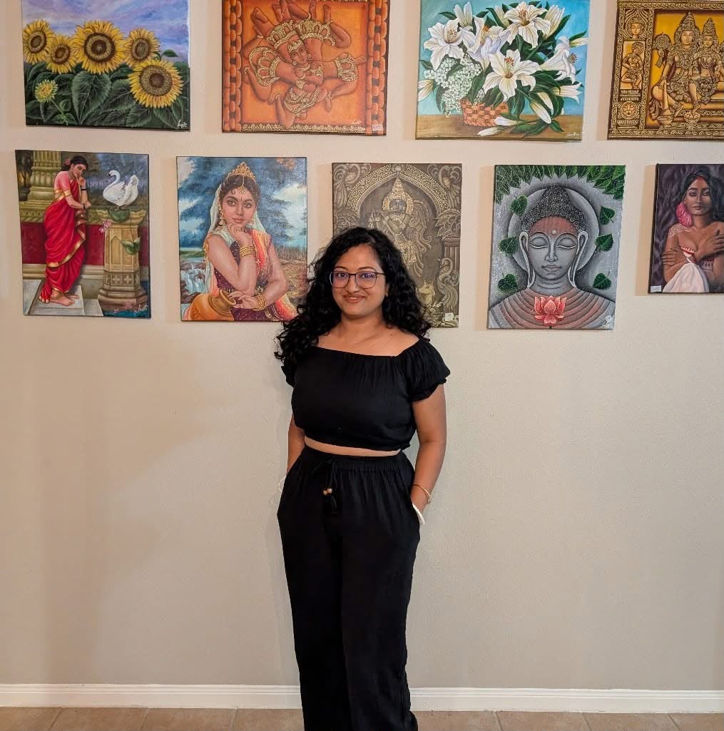 Anuradha Mondal standing in front of a wall of her original paintings